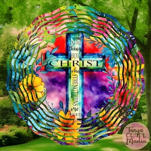 May include: A colorful metal wind spinner with a cross design and the words "I can do all things through CHRIST who strengthens me Phil 4:13". The cross is surrounded by flowers and leaves.