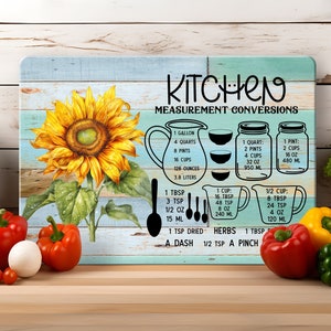 May include: A blue and white kitchen sign with a sunflower graphic and measurement conversions for US customary units. The sign reads "Kitchen Measurement Conversions".