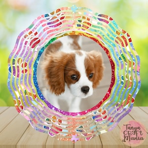 Puede incluir: Un molinillo de viento circular, colorido, brillante y de capas con una foto de un cachorro marrón y blanco en el centro. El molinillo de viento está sobre una superficie de madera. El texto "Tanya Craft Mania" está en la esquina inferior derecha de la imagen.