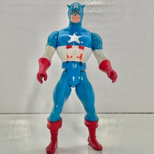 May include: A vintage action figure of Captain America, wearing his iconic red, white, and blue costume. The figure has a classic design and is in good condition.