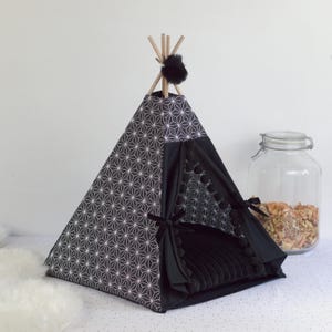 Peut inclure: Un tipi pour animaux de compagnie noir et blanc avec un motif g&eacute;om&eacute;trique. Le tipi contient un lit noir en peluche et est bord&eacute; de pompons noirs. Des poteaux en bois soutiennent le sommet, orn&eacute; d'un pompon noir.