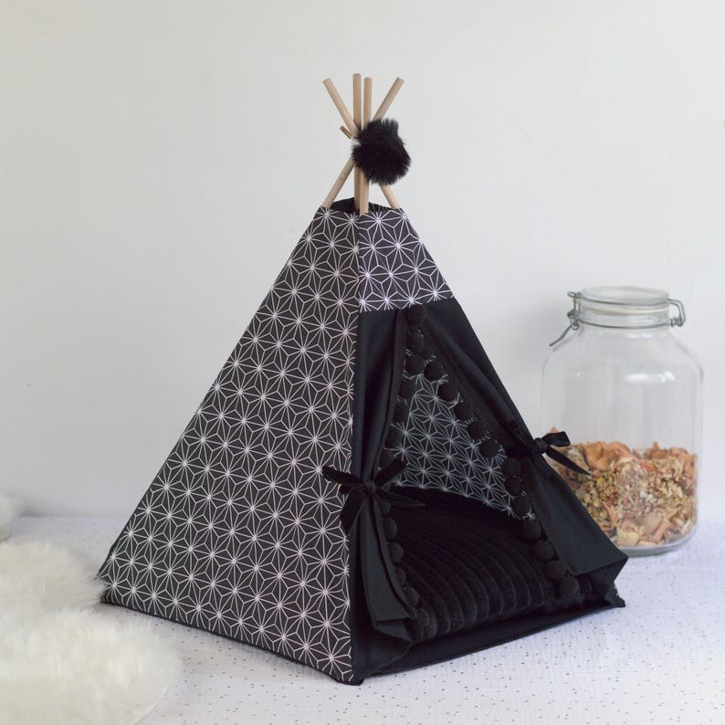 Peut inclure: Un tipi pour animaux de compagnie noir et blanc avec un motif g&eacute;om&eacute;trique. Le tipi contient un lit noir en peluche et est bord&eacute; de pompons noirs. Des poteaux en bois soutiennent le sommet, orn&eacute; d'un pompon noir.
