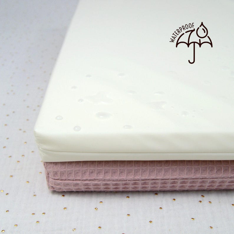 Zoom sur la housse imperméable d'un petit matelas de mousse pour lapin, cochon d'Inde et autres petits animaux. On voit des gouttes d'eau sur la surface pour illustrer la nature waterproof du coussin