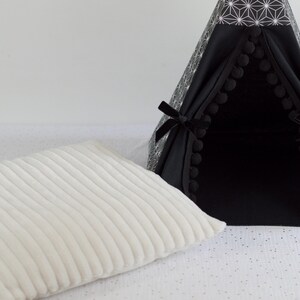 Gros plan sur un coussin crème côtelé en tissu minky avec un tipi noir et asanoha pour lapin, cochon d'inde, chinchilla, furet en arrière plan