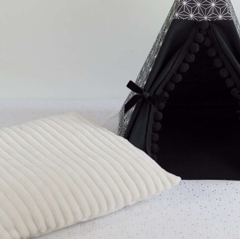 Gros plan sur un coussin crème côtelé en tissu minky avec un tipi noir et asanoha pour lapin, cochon d'inde, chinchilla, furet en arrière plan