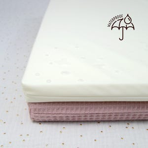 Zoom sur la housse imperméable d'un petit matelas de mousse pour lapin, cochon d'Inde et autres petits animaux. On voit des gouttes d'eau sur la surface.