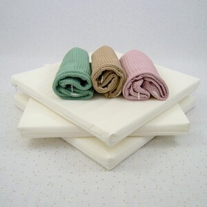 Photo de trois housses de rechange rose, vert sauge et marron clair en coton absorbant nid d'abeille pour petit matelas absorbant pour lapin de compagnie, cochon d'Inde et autres animaux de compagnie posées sur trois insert composés d'un matelas en mousse recouvert d'une housse à zip imperméable en tissu PUL