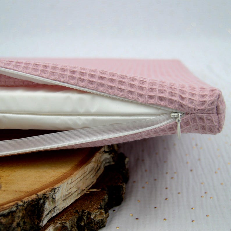 Zoom sur la fermeture éclair ouverte d'un petit matelas pour lapin et autres petits animaux pour visualiser l'insert glissé à l'intérieur composé d'un matelas en mousse recouvert d'une housse à zip imperméable en tissu PUL