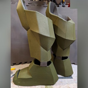 May include: A pair of green foam boots with a geometric design. The boots are made of foam and have a textured surface.