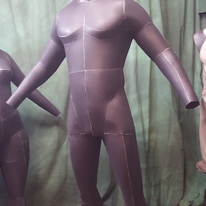 May include: A black, full-body mannequin with white lines drawn on it. The mannequin is standing on a wooden platform.