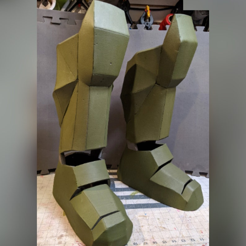 May include: A pair of green foam leg armor pieces, possibly for a costume or cosplay. The armor is made of foam and has a textured surface.