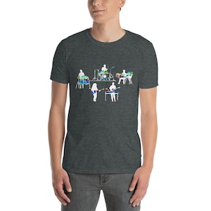 May include: A dark heather grey t-shirt with a white silhouette of a band playing music. The band members are playing guitar, bass, drums, and keyboard. The instruments are outlined in a colorful, abstract design.