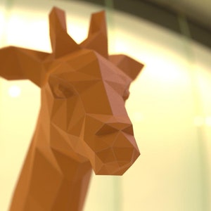 May include: A close-up of a brown origami giraffe head. The giraffe's head is made of paper and has a geometric design.