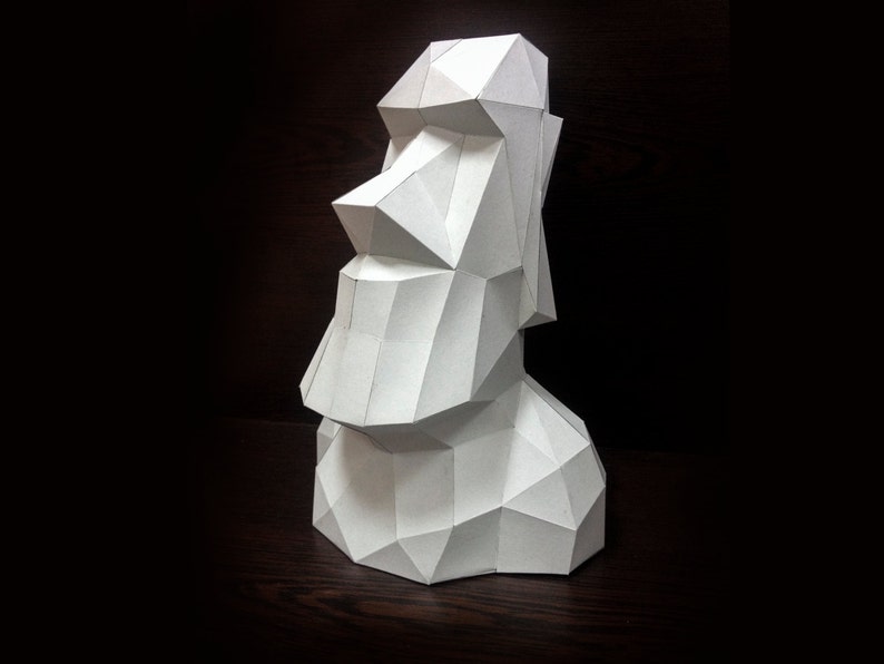 May include: A white paper model of a Moai statue, a traditional Easter Island head sculpture. The model is made of folded paper and has a geometric design.