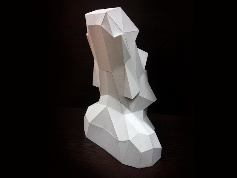 May include: A white paper sculpture of a geometric shape, resembling a stylized human figure. The sculpture is made of folded paper and has a textured surface.