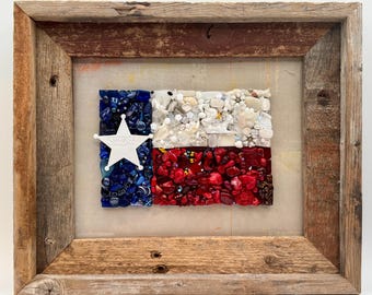 May include: A framed artwork depicting the Texas flag, crafted from various materials. The flag features blue, white, and red sections, with a white star in the blue field. The frame is made of rustic, weathered wood, adding a vintage aesthetic.