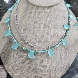 Puede incluir: Un collar de varias capas con una cadena de plata y cuentas turquesas. El collar presenta piedras turquesas en forma de l&aacute;grima que cuelgan de la cadena.