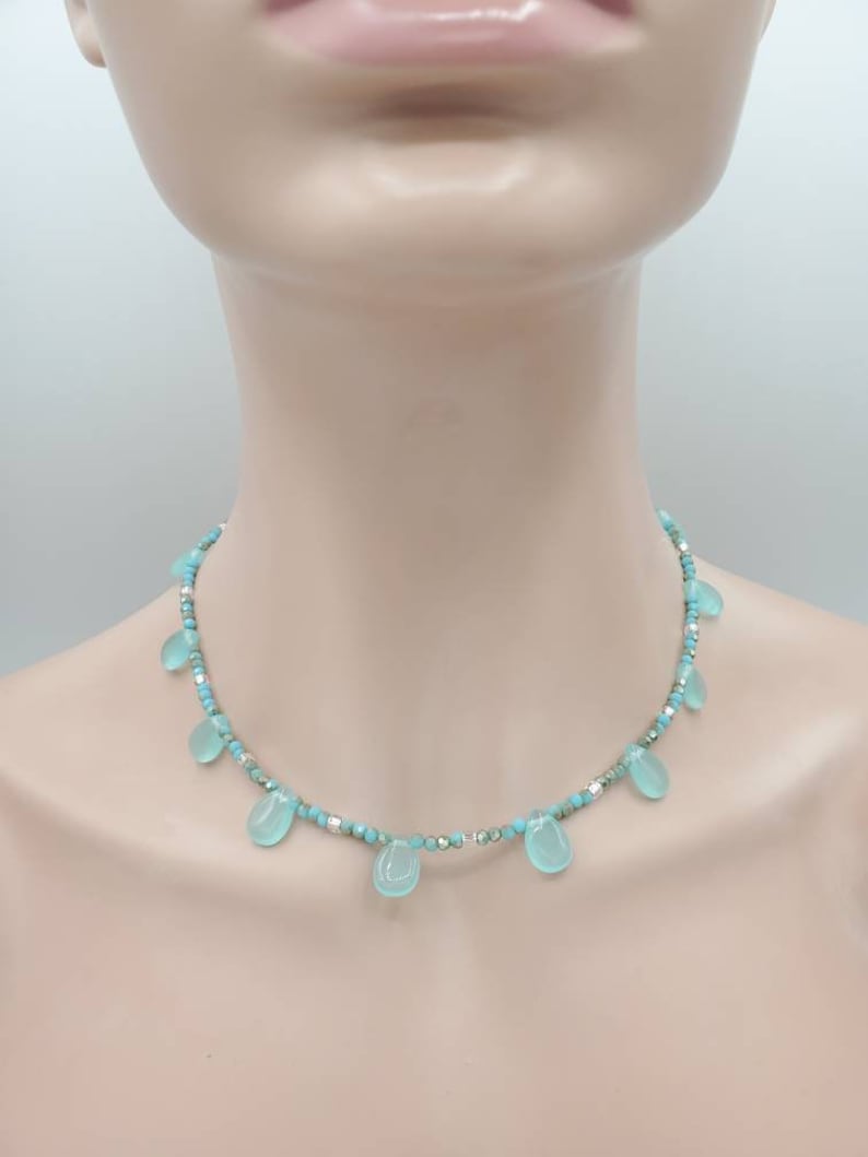 Puede incluir: Un delicado collar turquesa y plateado con cuentas en forma de l&aacute;grima.