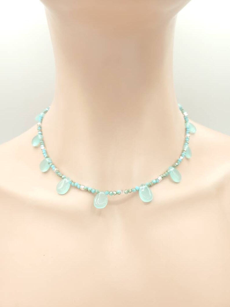 Puede incluir: Un delicado collar turquesa y plateado con cuentas de turquesa en forma de l&aacute;grima.