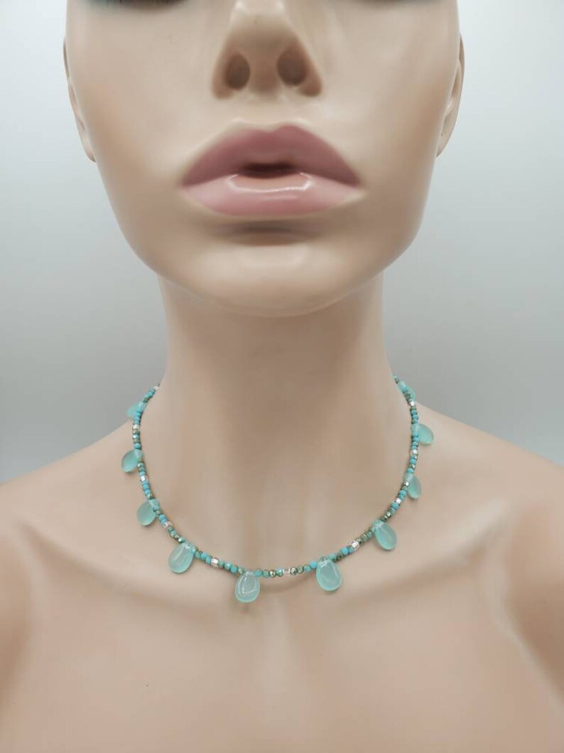 Puede incluir: Un collar turquesa y plateado con cuentas de turquesa en forma de l&aacute;grima.