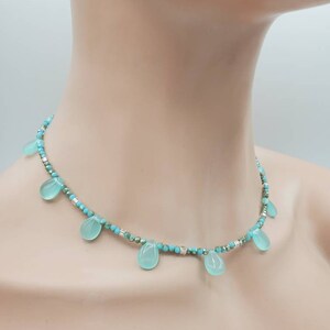 Puede incluir: Un collar de cuentas turquesa y plata con piedras turquesa en forma de l&aacute;grima que cuelgan de la cadena.