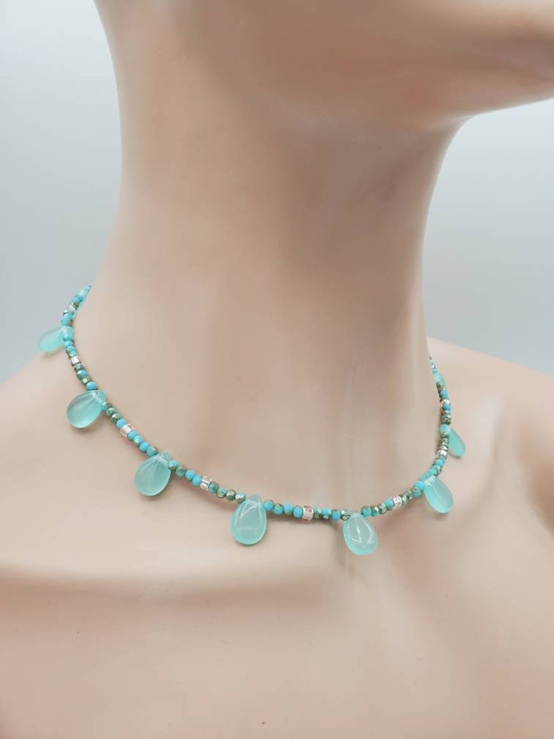 Puede incluir: Un collar de cuentas turquesa y plata con piedras turquesa en forma de l&aacute;grima que cuelgan de la cadena.