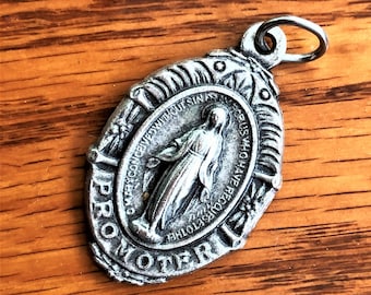 May include: Silver metal pendant featuring a depiction of the Virgin Mary with the words "PRO-MOTHER" and "AVE MARIA GRACIA PLENA DOMINUS TECUM" around the image.