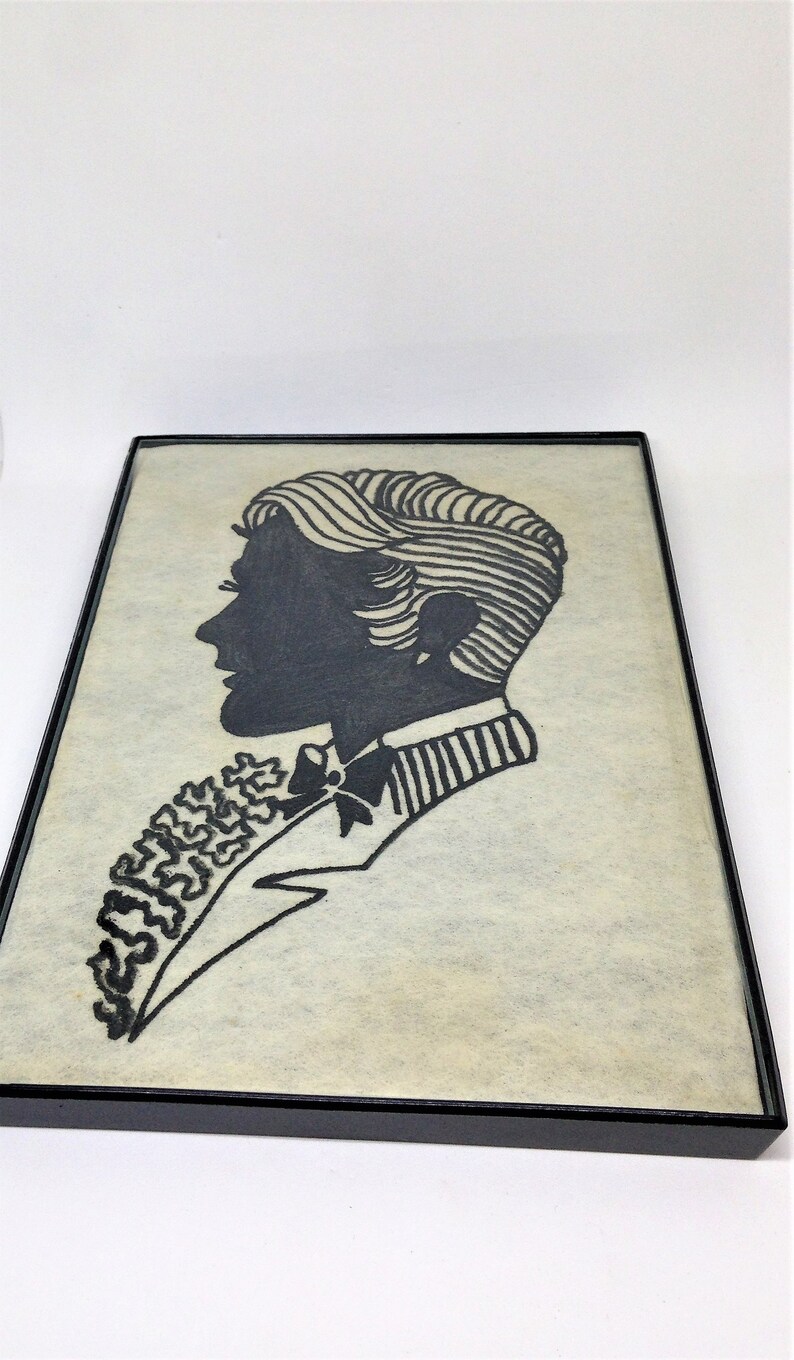 May include: Black and white silhouette of a person with a bow tie and a patterned shirt, framed in a black frame.