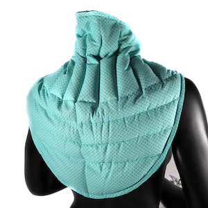 May include: A teal blue quilted neck wrap with a geometric pattern. The wrap is designed to provide warmth and comfort around the neck.
