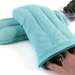 K&ouml;nnte beinhalten: Ein Paar t&uuml;rkisfarbene Ofenhandschuhe mit einem wei&szlig;en Rautenmuster. Die Handschuhe sind aus weichem, gestepptem Stoff gefertigt und haben eine dicke Isolierschicht, um Ihre H&auml;nde vor Hitze zu sch&uuml;tzen.
