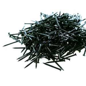 Pode incluir: Um grande monte de tachinhas pretas ou pregos de estofamento. As tachinhas s&atilde;o de metal e t&ecirc;m uma ponta afiada. S&atilde;o usadas para prender tecido a m&oacute;veis ou outras superf&iacute;cies.