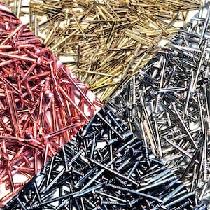 Op de afbeelding: Een vierkante compositie met diverse spijkers. De afbeelding is verdeeld in vier secties, elk met een andere metallic afwerking: koper, goud, zilver en zwart. De spijkers zijn van verschillende afmetingen en hebben een kop en een schroefdraad.