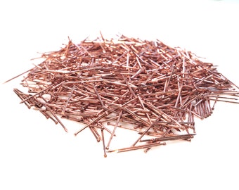 May include: A large pile of rose gold colored tacks or push pins.