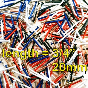 Puede incluir: Un conjunto de clavos pequeños en varios colores, incluyendo rojo, blanco, azul, negro y dorado. Los clavos miden 20 mm de largo, como indica el texto en la imagen. Los clavos están dispersos por la superficie.