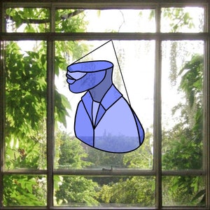 May include: A window with a view of a lush green garden. A blue and white illustration of a person wearing a suit is hanging in the window.