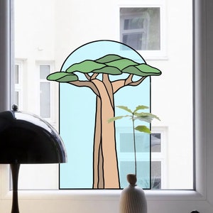 May include: A stained glass window sticker featuring a stylized tree with a brown trunk and green leaves. The sticker is set against a blue background and is framed by a white window.