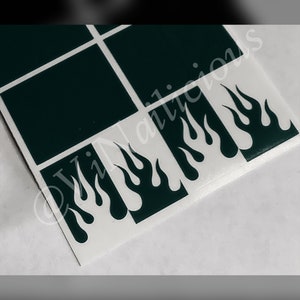 May include: A sheet of black and white nail decals with a flame design. The decals are arranged in a grid pattern.
