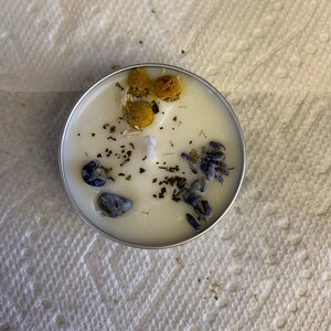 May include: A white candle with dried lavender, chamomile, and blue stones embedded in the wax.