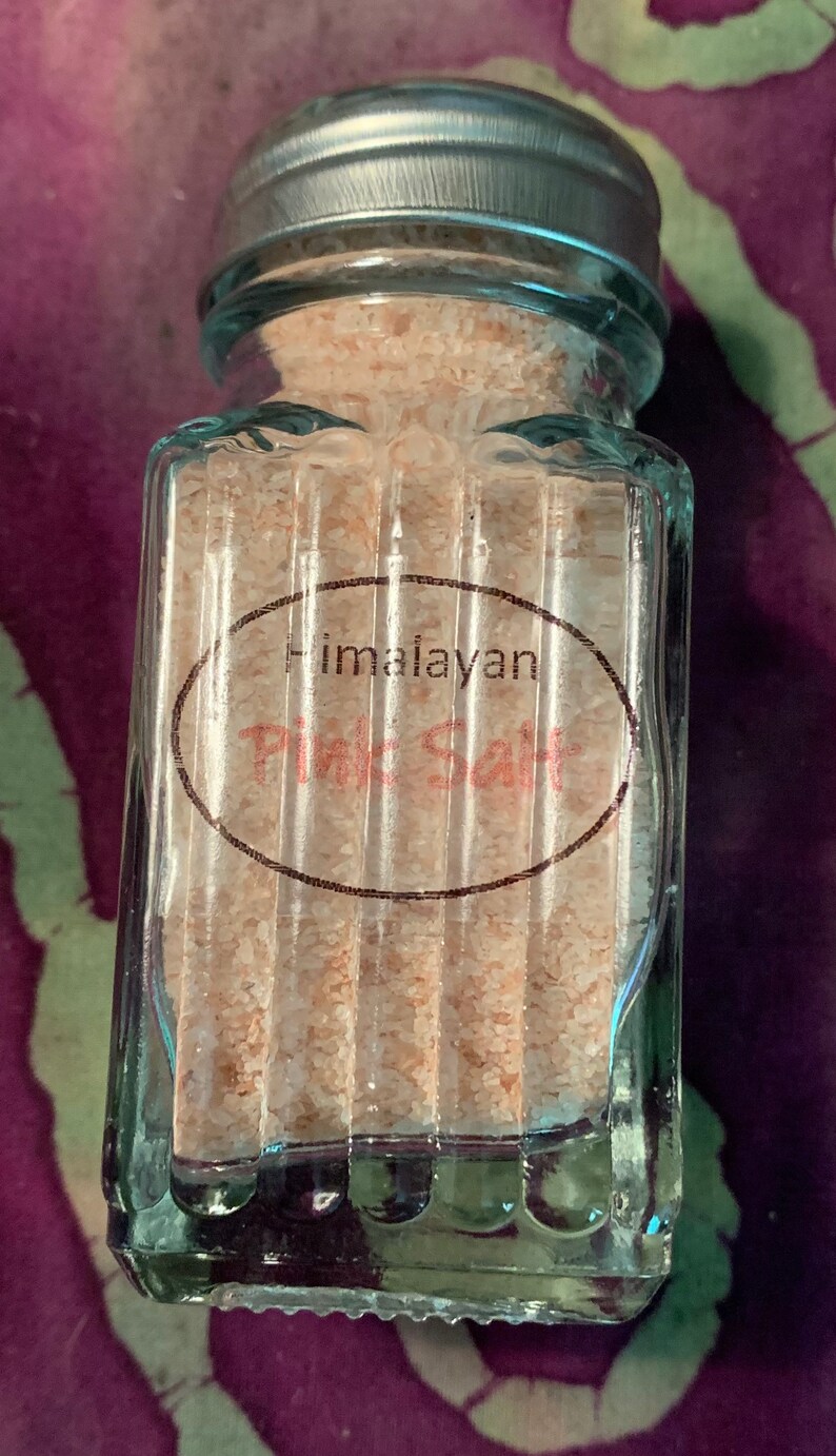 May include: A glass jar with a silver lid filled with pink Himalayan salt. The jar has a label that reads "Himalayan Pink Salt".