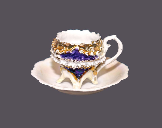 German barbotine four-footed demitasse cup and saucer set. Lusterware cobalt details. Flaws (see below).