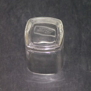 Peut inclure: Un verre &agrave; boire en verre transparent de forme carr&eacute;e avec un fond l&eacute;g&egrave;rement arrondi. Le verre a un bord sur&eacute;lev&eacute; et une surface lisse. Le fond du verre porte l'inscription "Keez-Whizz".