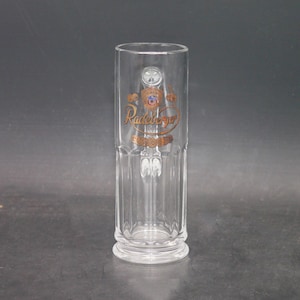 May include: A clear glass beer stein with a gold logo that reads "Radeberger" and a gold crest.