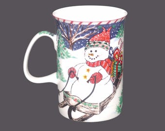 Royal Heritage Christmas coffee or tea mug. Snowman riding on sled with presents, candy cane border.