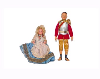 Pair of jointed plastic, hand-painted dolls. Boy in British Officer's red-coat uniform, girl with bonnet, cross.