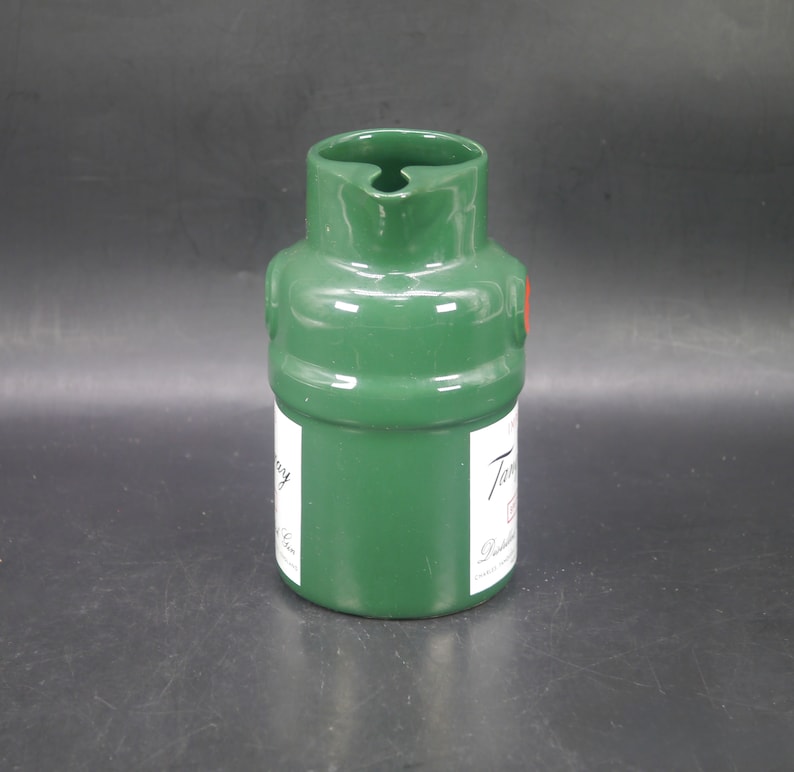 May include: Green ceramic pitcher with a red dot and the text "Tanqueray" in white lettering. The pitcher is shaped like a bottle.