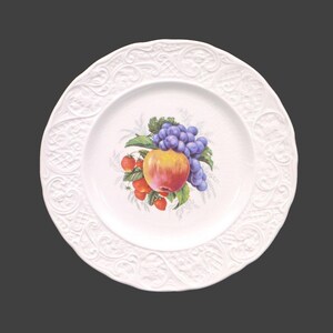 May include: White ceramic plate with an embossed design around the edge. The center of the plate features a painted image of a red apple, grapes, and strawberries.