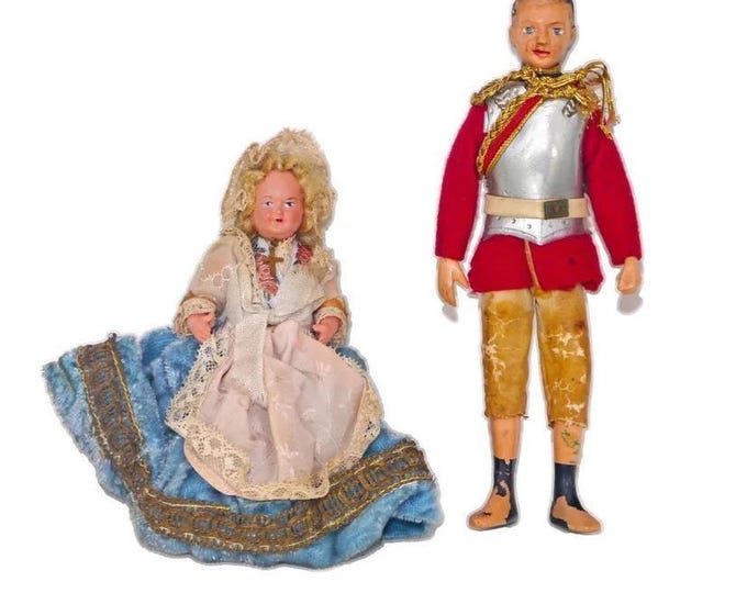 Pair of jointed plastic, hand-painted dolls. Boy in British Officer's red-coat uniform, girl with bonnet, cross.