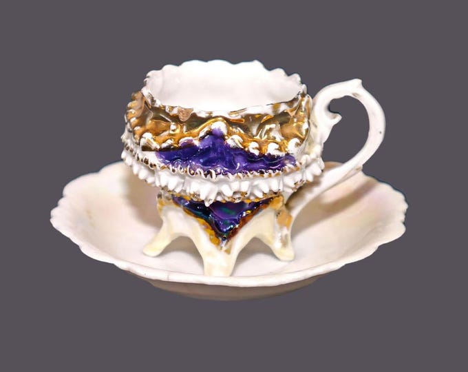 German barbotine four-footed demitasse cup and saucer set. Lusterware cobalt details. Flaws (see below).
