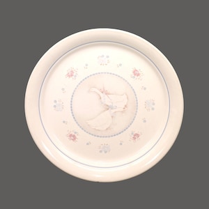 May include: A white ceramic plate with a blue and pink floral design and a pair of white birds in the centre.