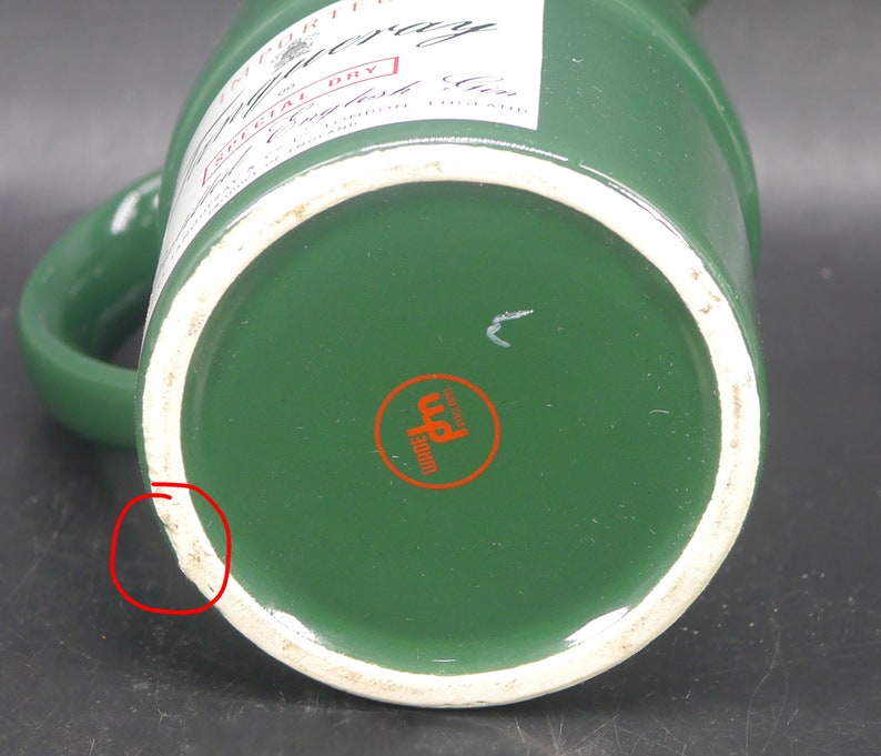 May include: Green ceramic pitcher with a white rim and a label that reads "IMPORTED" "Gilbey's" "SPECIAL DRY" "English Gin" and "MADE & BOTTLED IN ENGLAND". The bottom of the pitcher has a red circle with the word "WARRE" and a symbol inside.